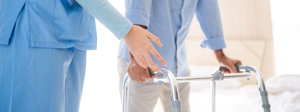 歩行器を使う利用者を介護職員が支える様子